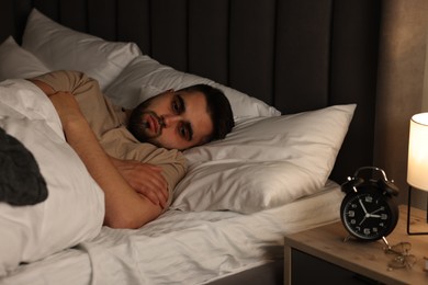 Photo of Frustrated man suffering from insomnia in bed