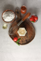 Photo of Pizza dough starter in glass jar, products and whisk on gray textured table, flat lay