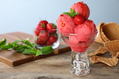 Photo of Delicious strawberry ice cream in dessert bowl on wooden table against light background, space for text