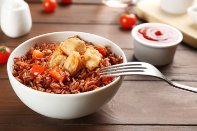 Photo of Delicious brown rice in bowl on wooden table