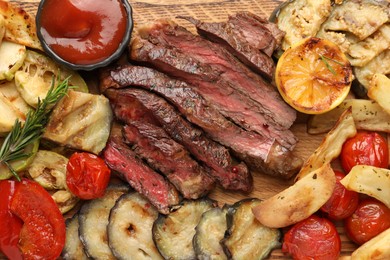 Photo of Delicious grilled beef with vegetables, rosemary and tomato sauce on table, top view