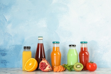 Photo of Bottles with different drinks and ingredients on table against color background