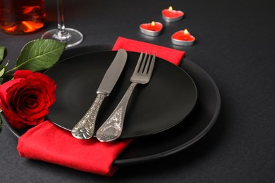 Photo of Beautiful table setting with burning candles and rose on black table for romantic dinner