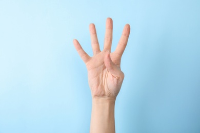 Photo of Woman showing number four on color background, closeup. Sign language
