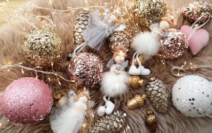 Photo of Beautiful Christmas tree baubles, toys and fairy lights on faux fur, above view
