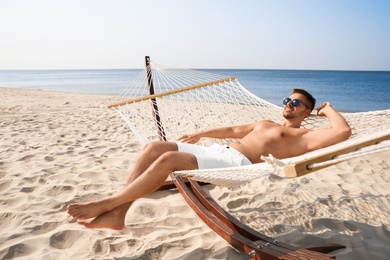 Photo of Young man relaxing in hammock on beach