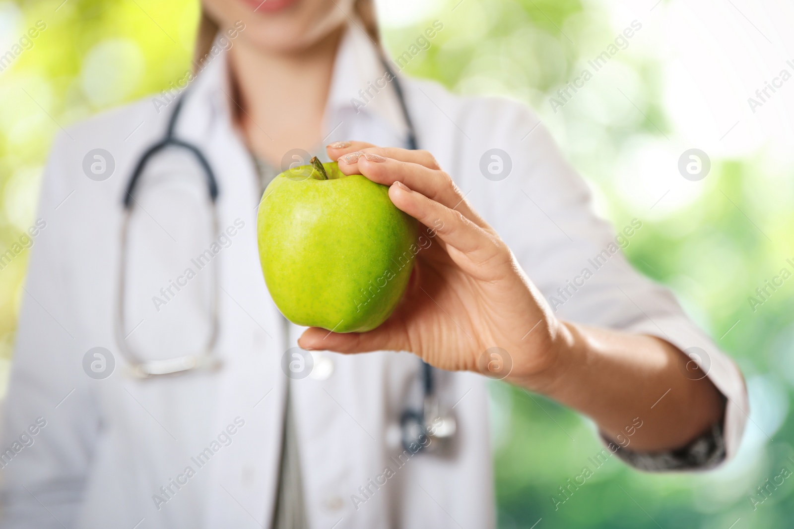 Image of Nutritionist with fresh apple on blurred green background, closeup
