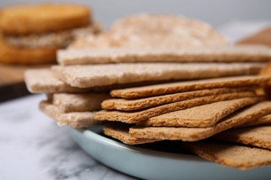 Photo of Rye crispbreads, rice cakes and rusks on white marble table, closeup