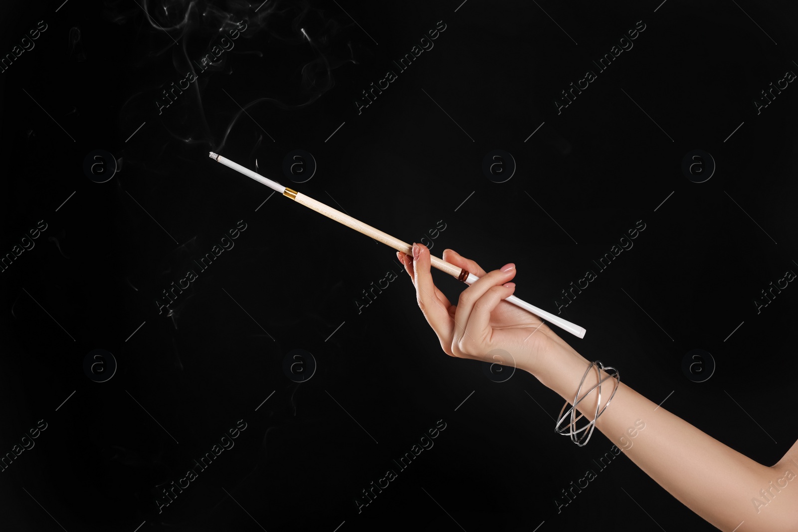 Photo of Woman holding long cigarette holder on black background, closeup