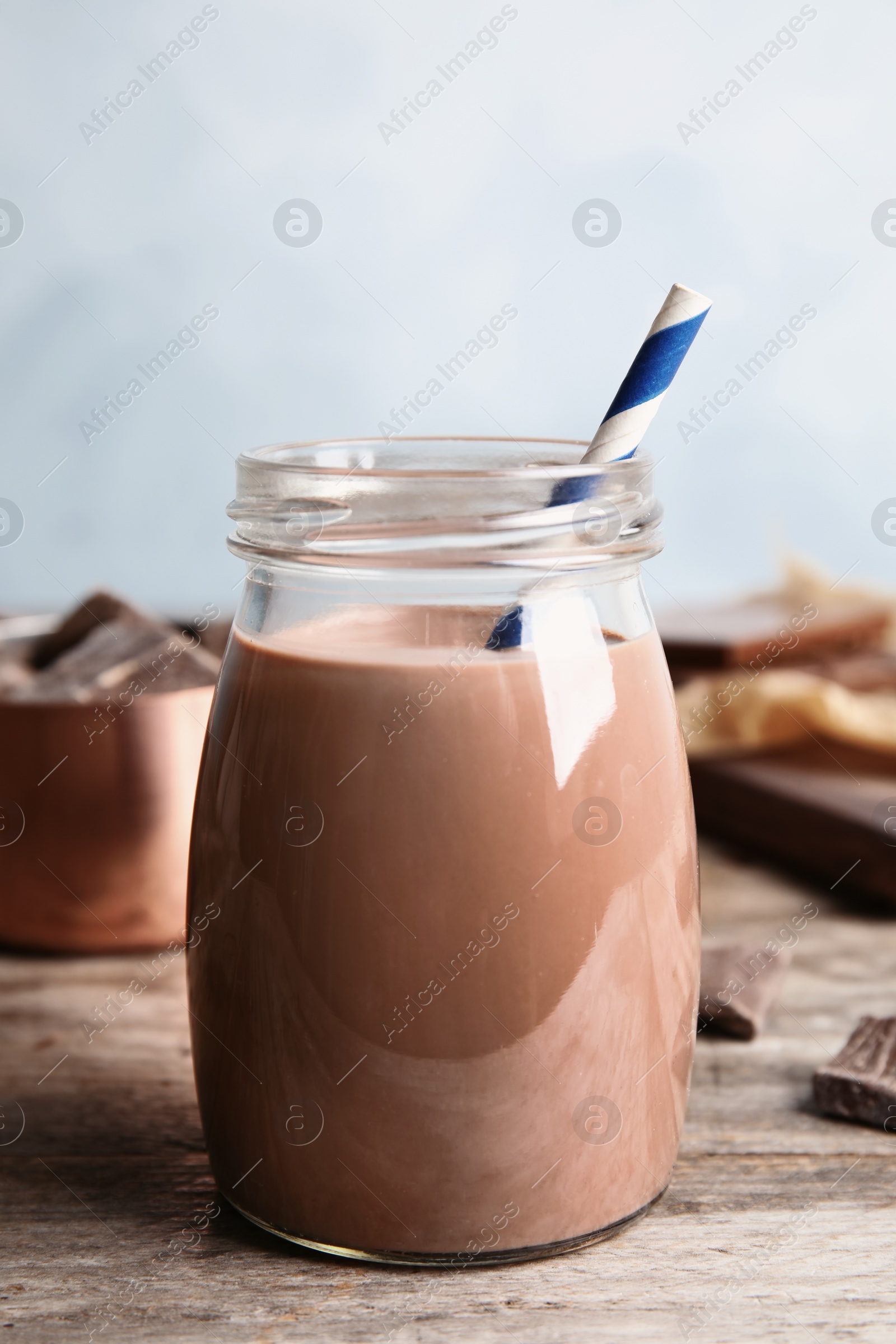 Photo of Jar with tasty chocolate milk on wooden table. Dairy drink