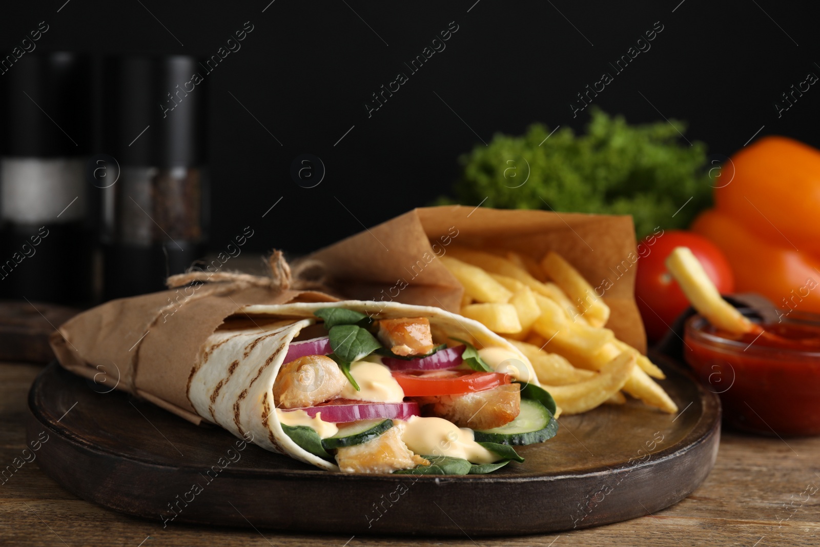 Photo of Delicious chicken shawarma and French fries on wooden table