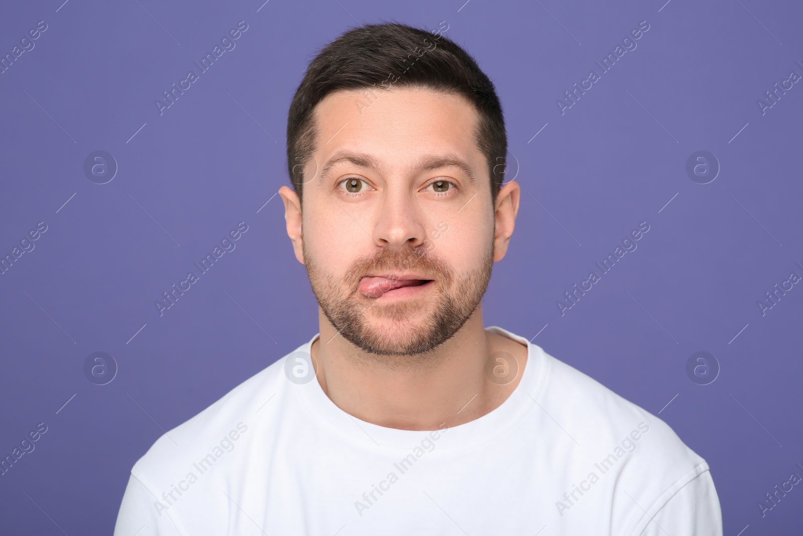 Photo of Man showing his tongue on purple background