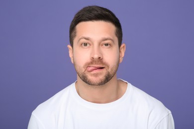 Photo of Man showing his tongue on purple background