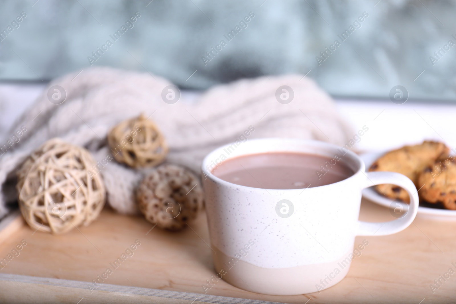 Photo of Cup of aromatic cacao on wooden tray near window, closeup