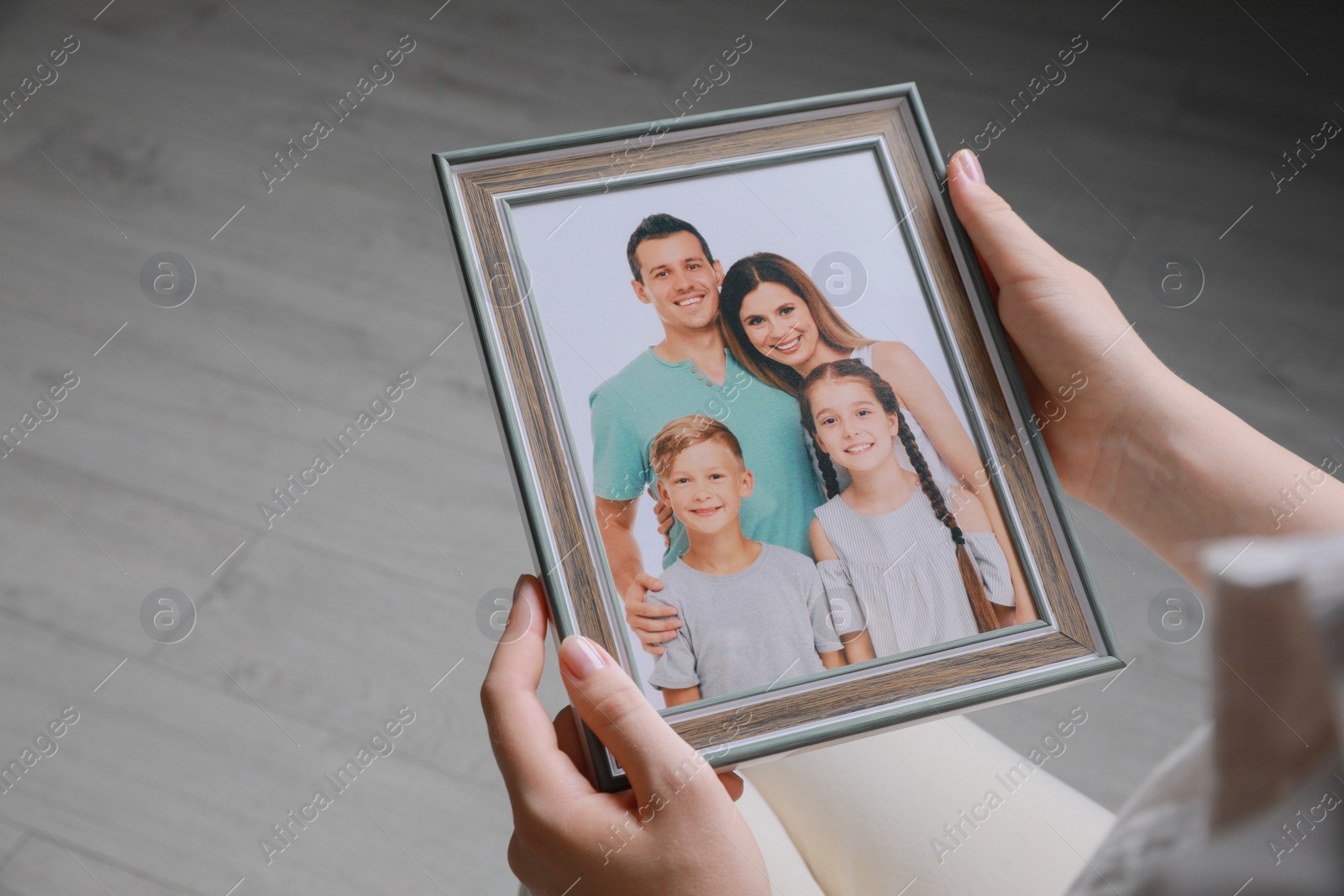 Photo of Woman holding framed family photo indoors, closeup