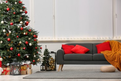 Soft sofa near Christmas tree and accessories in stylish room. Interior design