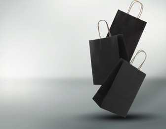 Image of Hot sale. Black shopping bags in air on light gradient background, space for text