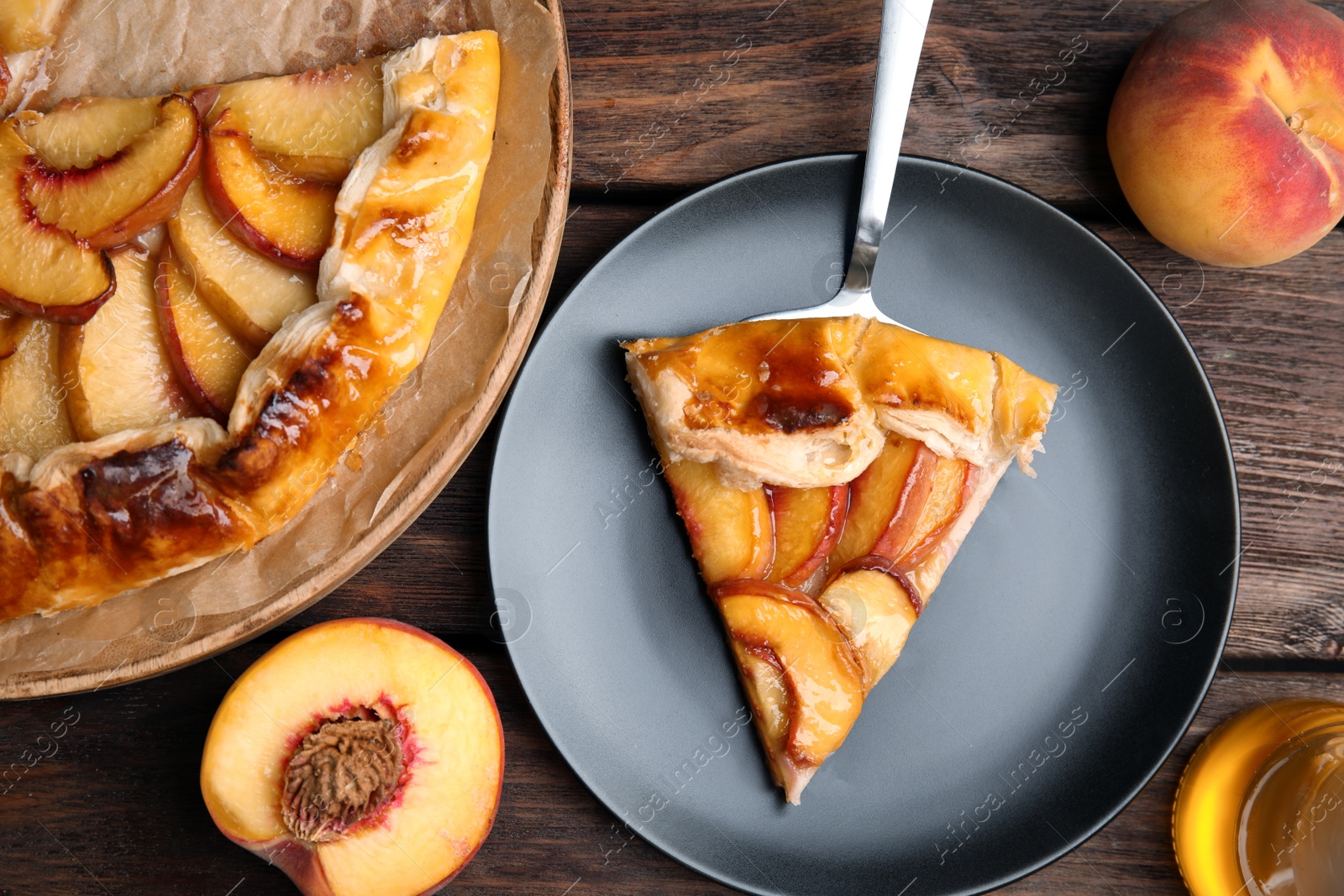 Photo of Delicious fresh peach pie served on wooden table, flat lay