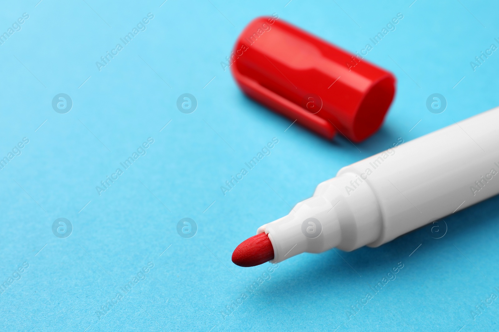 Photo of Bright red marker on light blue background, closeup. Space for text