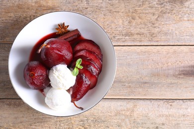 Photo of Tasty red wine poached pears and ice cream in bowl on wooden table, top view. Space for text