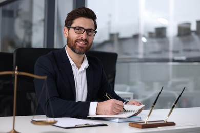 Smiling lawyer working at table in office, space for text