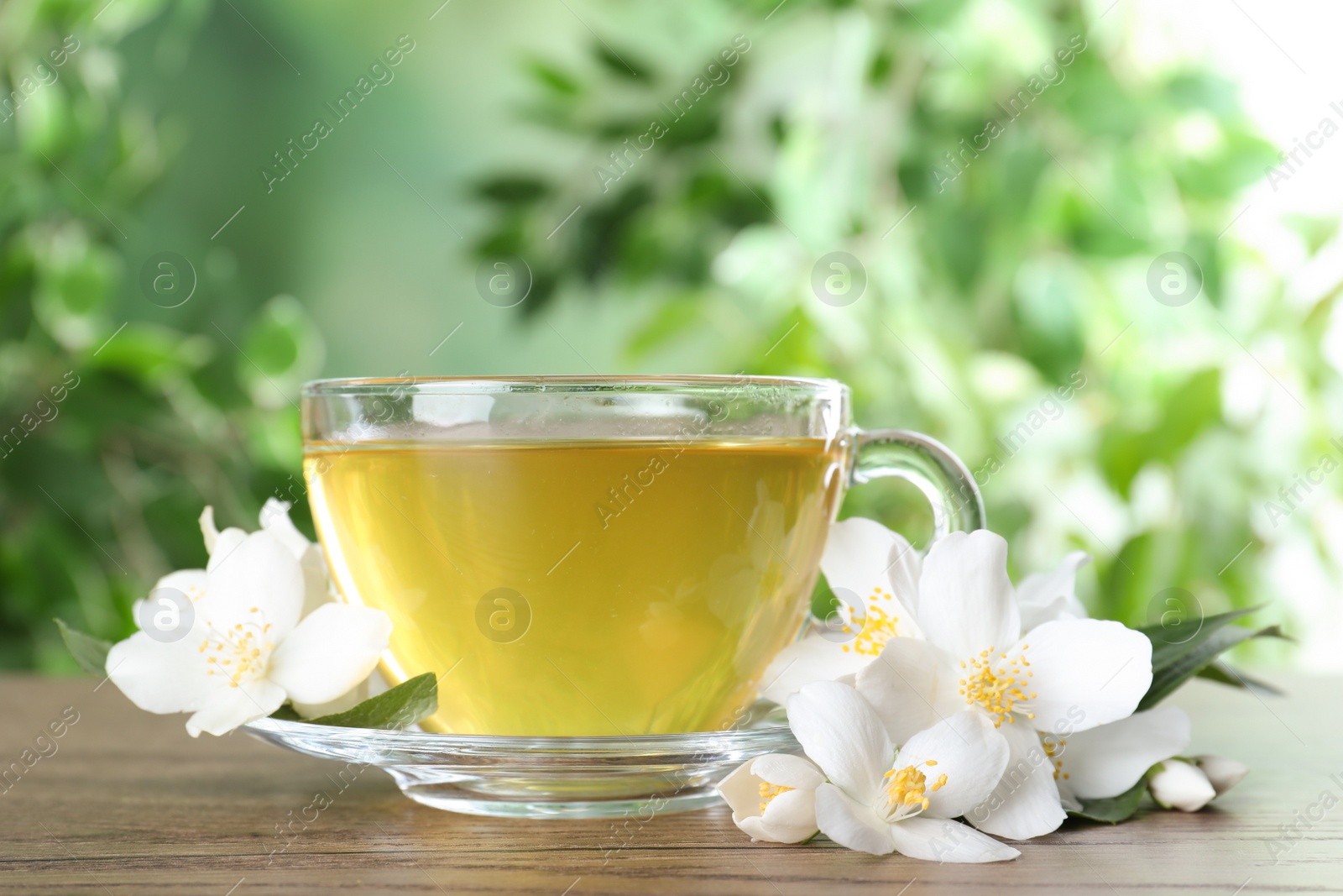 Photo of Cup of tea and fresh jasmine flowers on wooden table