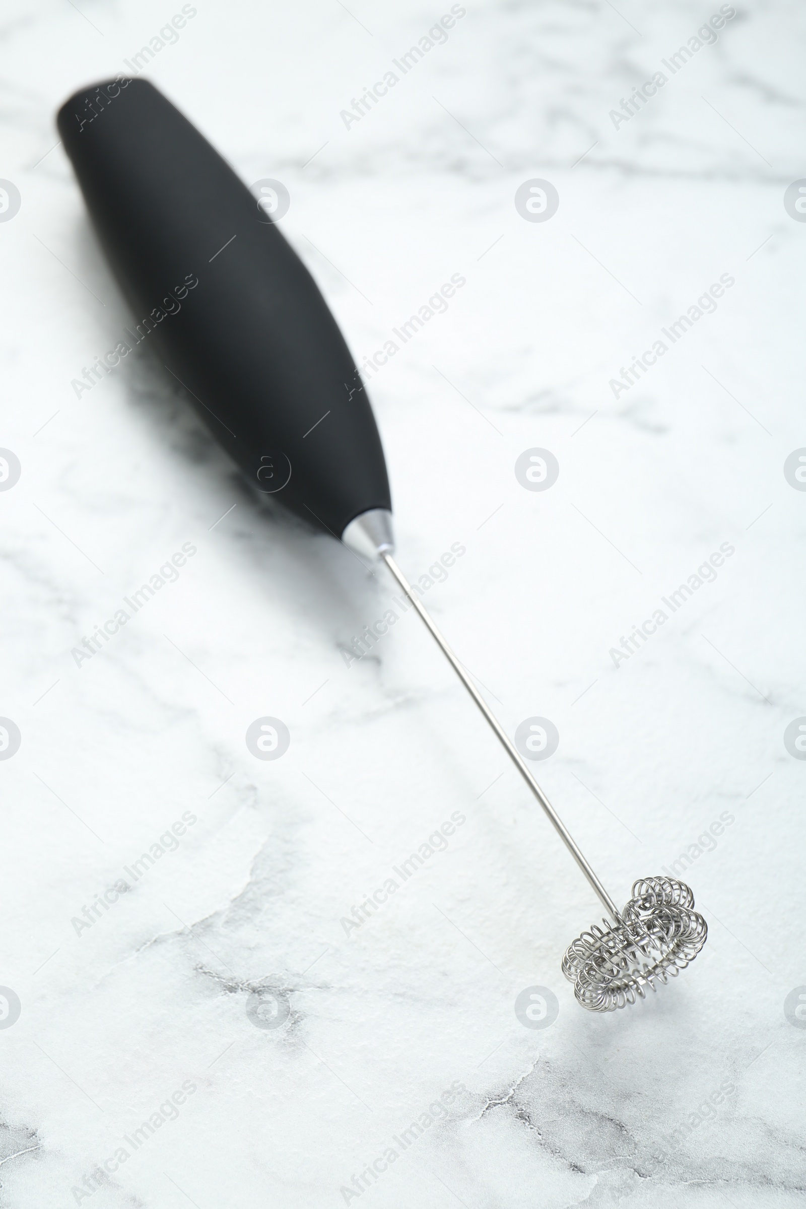 Photo of Black milk frother wand on white marble table, above view