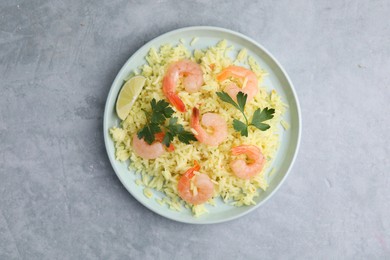 Photo of Delicious risotto with shrimps, lime and parsley on light grey table, top view