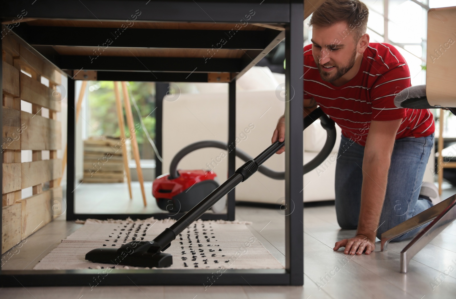 Photo of Young man using vacuum cleaner at home