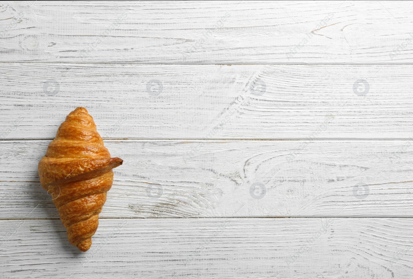 Photo of Tasty croissant and space for text on white wooden background, top view. French pastry