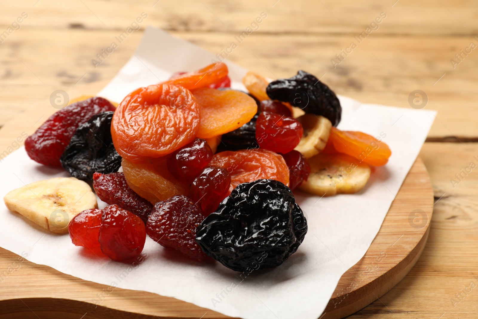 Photo of Mix of delicious dried fruits on wooden table, closeup