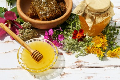 Photo of Delicious honey, combs and different flowers on white wooden table