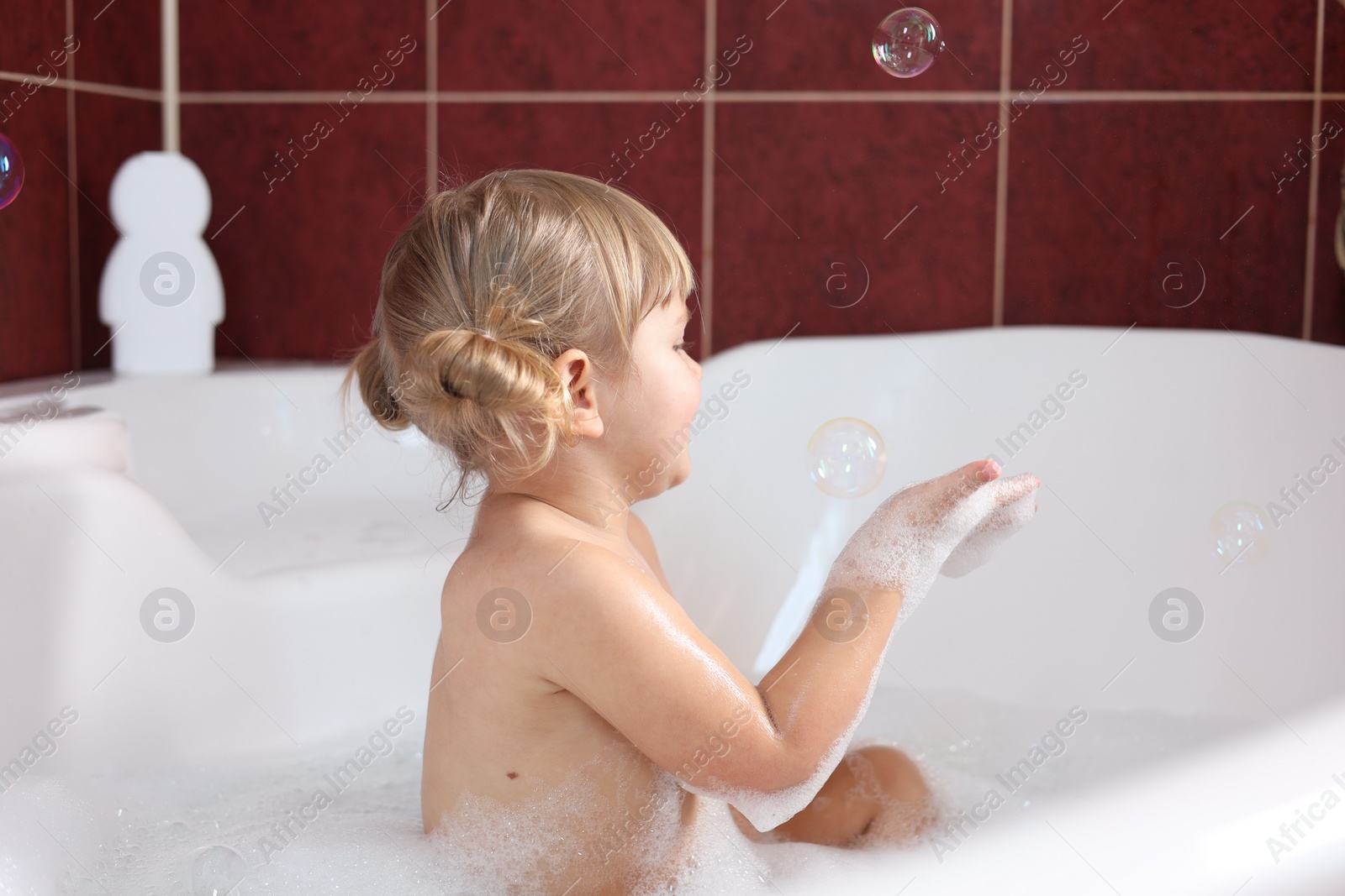 Photo of Little girl having fun in bathtub at home