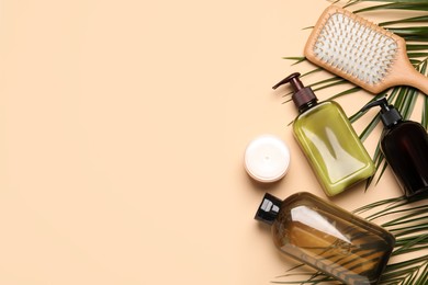 Photo of Shampoo bottles, hair mask, hair brush and palm leaf on beige background, flat lay. Space for text