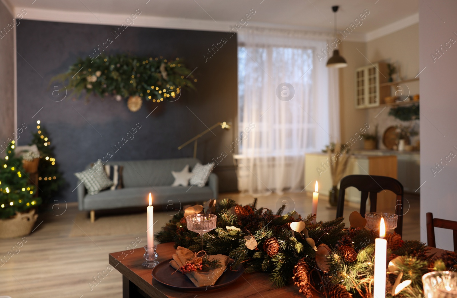 Photo of Stylish living room with comfortable sofa, burning candles and Christmas decor. Interior design