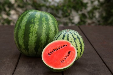 Photo of Delicious cut and whole ripe watermelons on wooden table