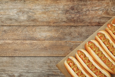 Hot dogs with mustard and space for text on wooden background, top view