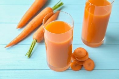 Photo of Glasses with carrot juice and fresh vegetable on wooden table
