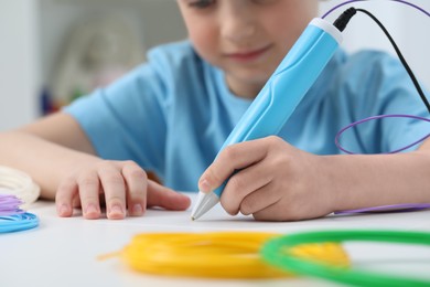 Photo of Girl drawing with stylish 3D pen at white table indoors, selective focus