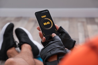 Photo of Man using fitness app on smartphone indoors, closeup