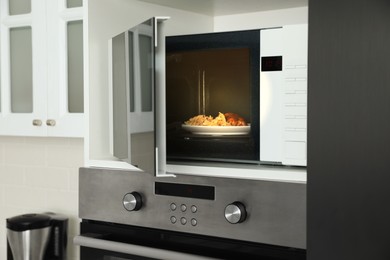 Photo of Open microwave oven with food on white shelf in kitchen