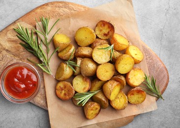 Photo of Tasty baked potato with aromatic rosemary and sauce served on grey textured table, flat lay