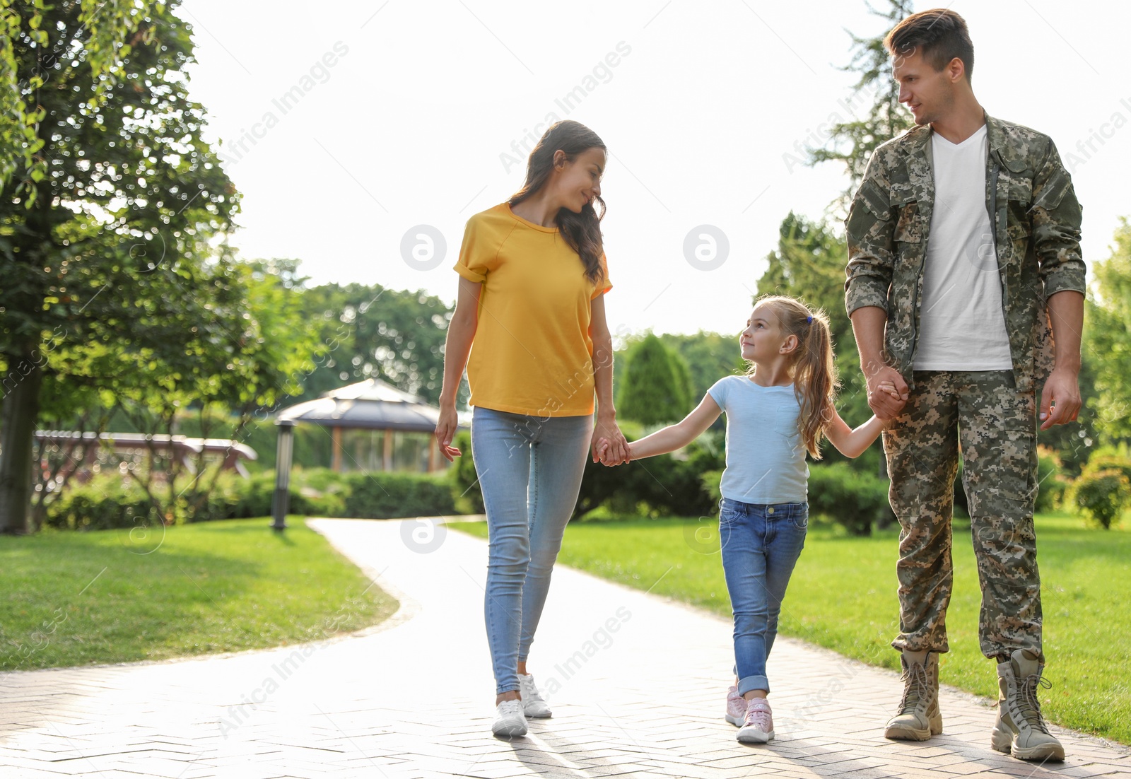 Photo of Man in military uniform and his family walking at sunny park