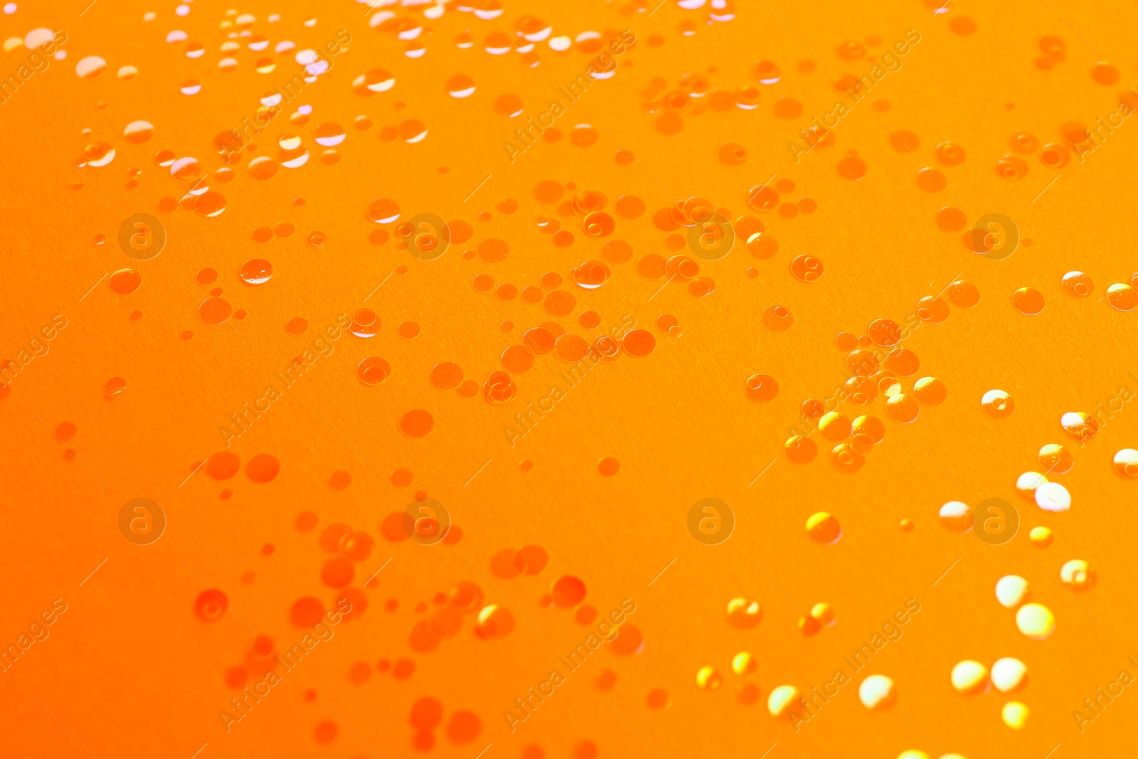 Photo of Shiny bright glitter scattered on orange background