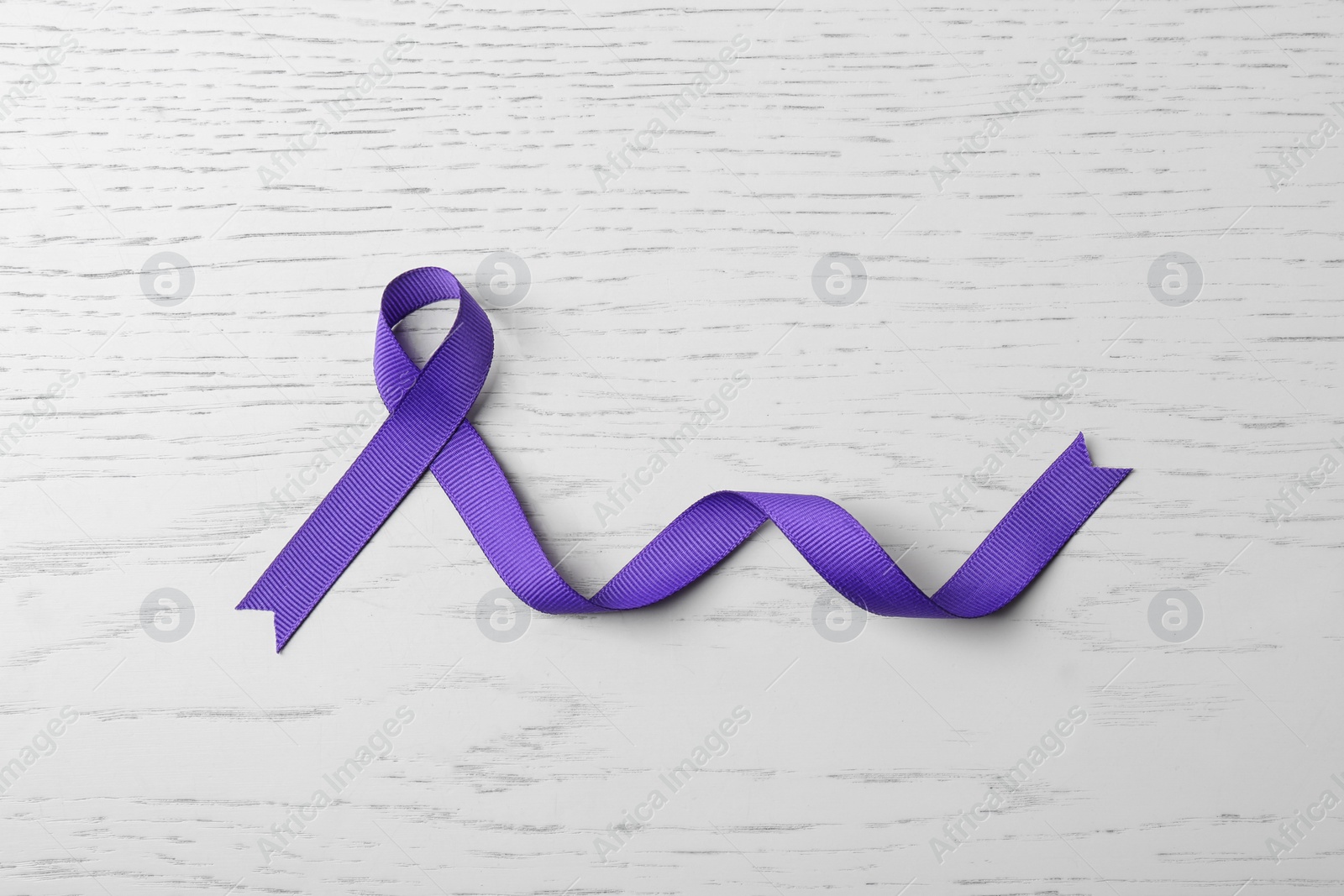 Photo of Purple ribbon on white wooden background, top view. Domestic violence awareness