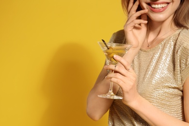 Photo of Young woman with glass of martini cocktail on color background, closeup. Space for text