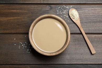 Photo of Tasty sesame paste, seeds and spoon on wooden table, flat lay