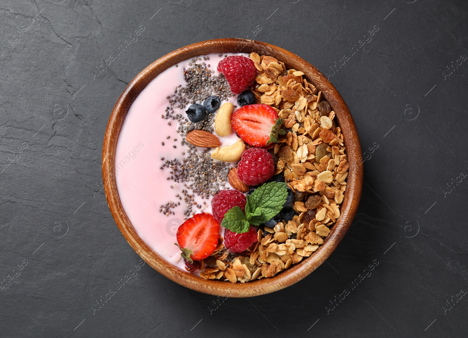 Photo of Tasty homemade granola with yogurt on dark grey table, top view. Healthy breakfast