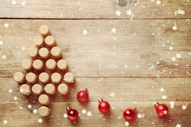 Image of Christmas tree made of wine corks and baubles on wooden table, flat lay. Space for text
