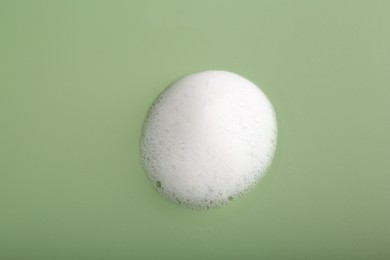 Sample of fluffy foam on green background, top view